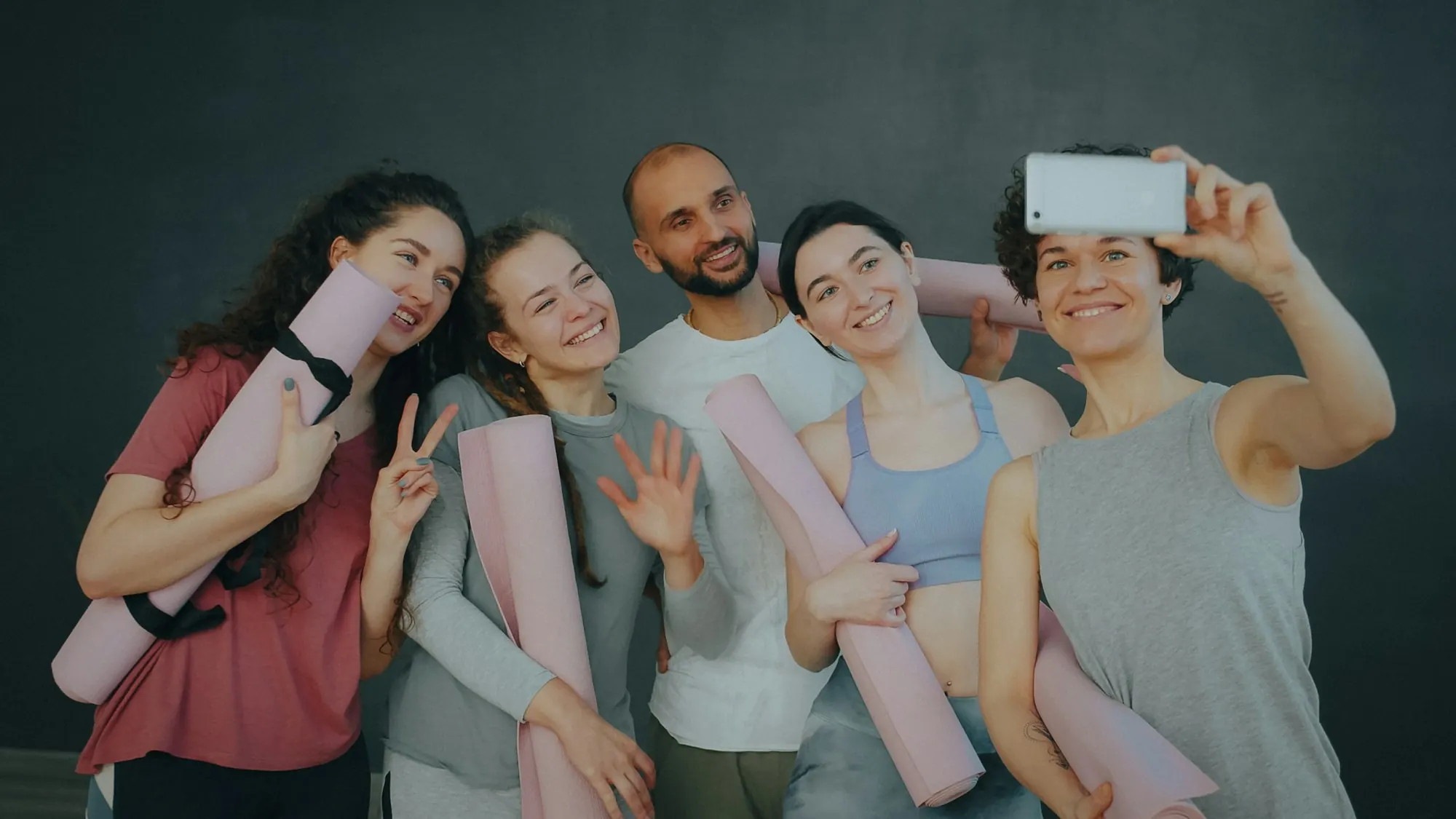 Fünf Kursanbietende mit Yogamatten stehen zusammen in einem Studio